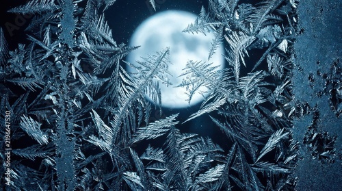 Frozen window pane with moon in winter night.