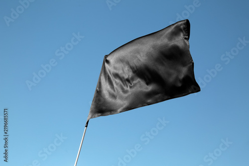 Foto Protest and mourning black flag waving in the wind on a clear blue sky as a sign