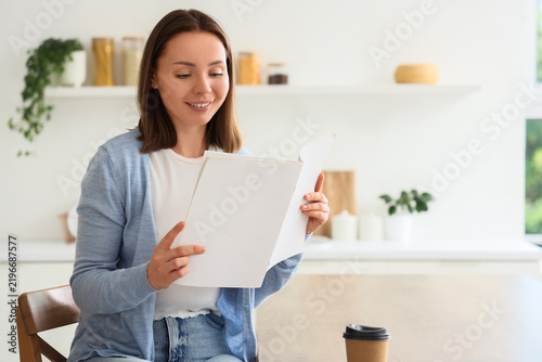 Mindfulness and leisure, woman reading a magazine at home with a coffee cup i...