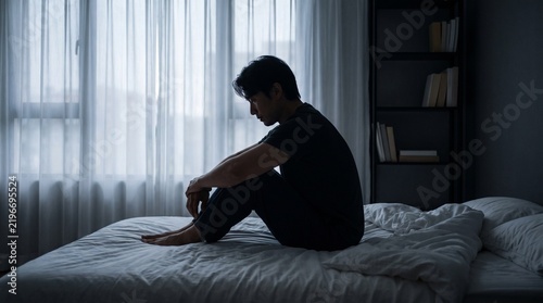 Quiet Moment of Sadness and Reflection Featuring Lonely Man Sitting Alone on Bed in Dim Bedroom