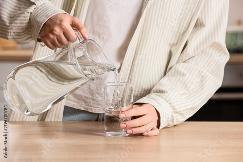 Bild auf Leinwand Hydration and healthy lifestyle, person pouring fresh water from glass pitcher i