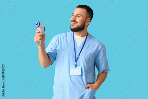 Male doctor with infrared thermometer on blue background