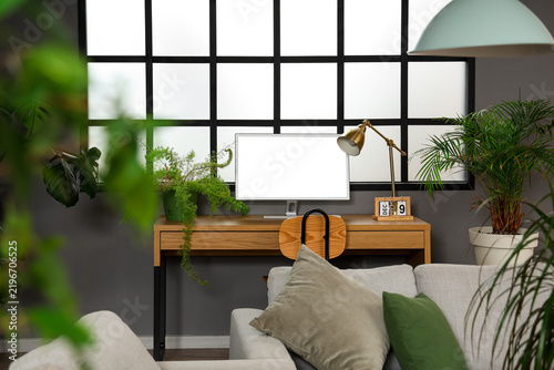 Workplace with computer and green plant in stylish living room
