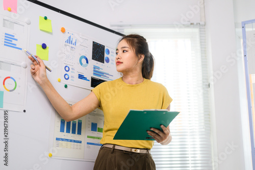 Young asian businesswoman analyzing business data charts on whiteboard