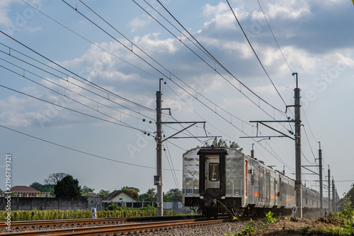 Rear view of a passenger train passing under electrical overhead lines