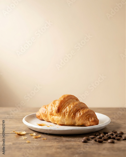 Photorealistic food advertisement of one golden flaky butter croissant on a white ceramic plate, a few crumbs and coffee beans, warm cream studio background, soft morning light, refined minimal bakery