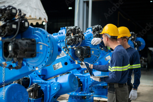Engineers inspecting industrial robot arm in factory