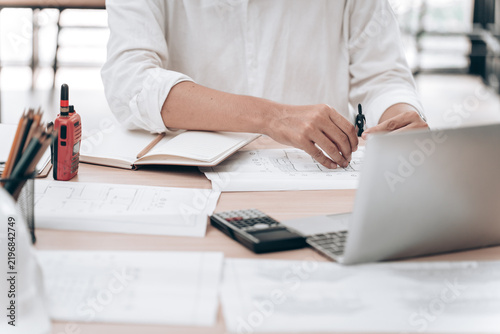 Person Working at Desk with Paperwork and Laptop in a Modern Office Environment