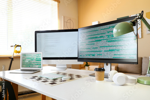 Software development and remote work, programmer workspace with multiple moni...