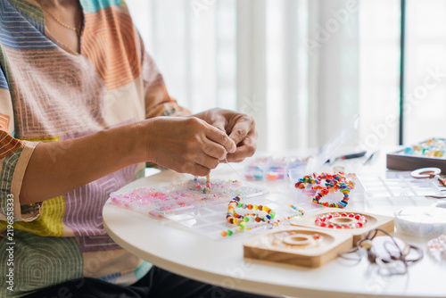 Mature Asian woman making necklace handcrafted