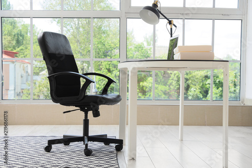 Remote work and home office setup, empty desk with laptop and chair in bright...