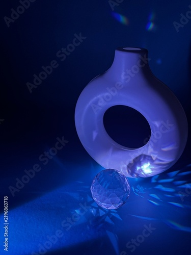 Abstract blue still life with decorative vase and crystal sphere creating prismatic light reflections