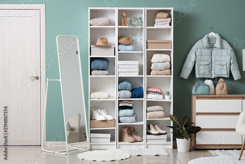 Shelving unit with winter female clothes and accessories in stylish room