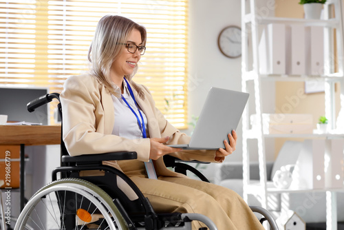 Young businesswoman working with laptop in wheelchair at office