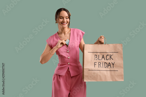 Young woman holding shopping bag with text BLACK FRIDAY and credit card on gr...