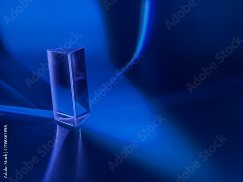 Transparent glass prism with blue light refraction and glowing abstract reflections