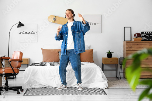 Young man with headphones dancing in bedroom