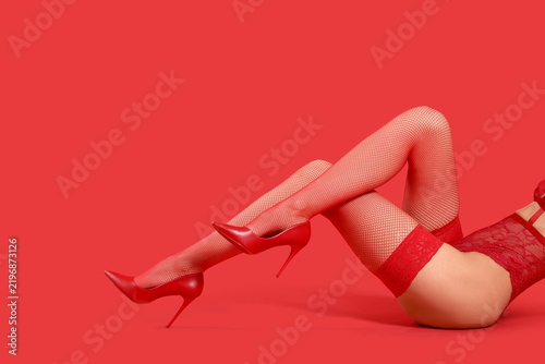 Canvastavla Sexy young woman in stockings with high heels on red background