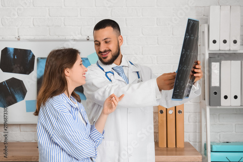 Male doctor showing MRI scan of spine to patient in clinic