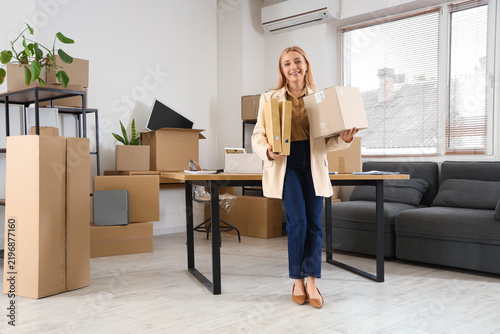 Mature businesswoman with box and folders in office on moving day