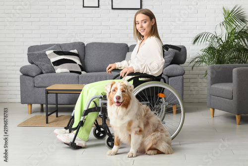 Young woman in wheelchair with service dog at home