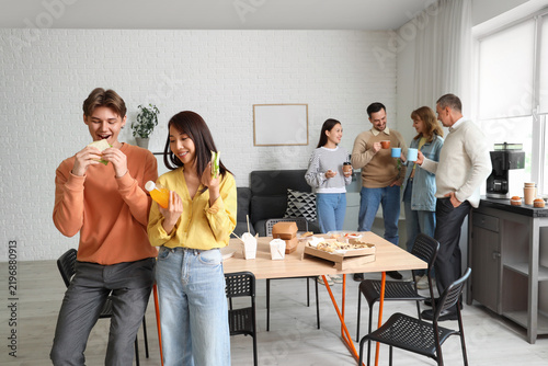 Business people with sandwiches having lunch in office kitchen