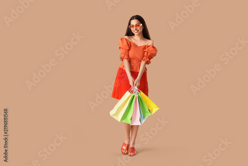 Beautiful young happy woman with shopping bags on brown background. Summer sa...