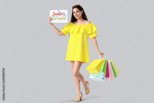 Beautiful young happy woman holding shopping bags and paper with text SUMMER ...