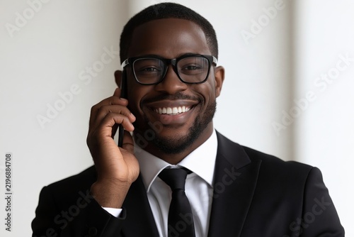 Smiling african american businessman talking on a smartphone in a bright office