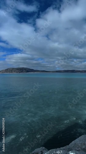 Peaceful Blue Bay Surrounded by Green Hills Under Cloudy Sky
