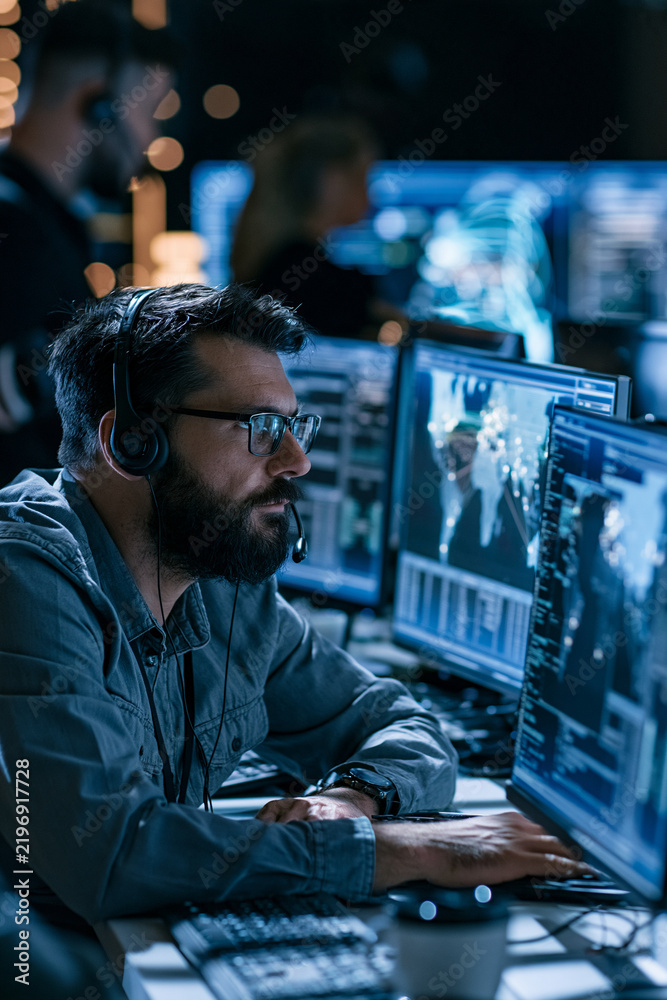 Fototapeta premium cybersecurity analyst monitoring security dashboard on multiple screens, dark modern operations center, realistic stock photography