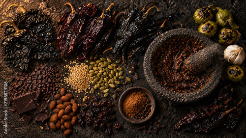 Mexican mole poblano ingredients dark flatlay overhead ancho mulato pasilla chili cacao molcajete volcanic stone authentic cuisine food