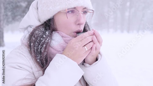 Woman outdoor lifestyle. Female drinking tea during snowfall. Mindful living concept.