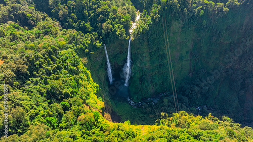 Foto Aerial view of Tad Fane Waterfall in Laos, with a tourist enjoying tea while suspended on a zipline above the spectacular twin cascades and lush rainforest of the Bolaven Plateau