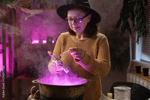 Obraz na plátně realistic witch holding voodoo doll casts spell brewing potion in cauldron