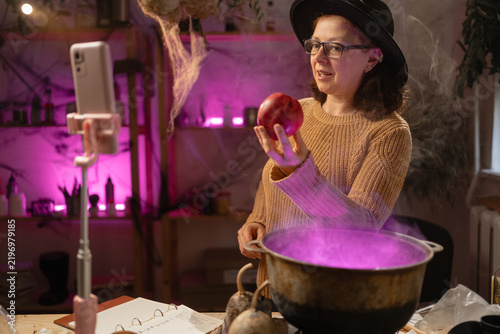 Fotografie realistic witch vlogger reviewing brewing potion in cauldron, broadcasting on social media