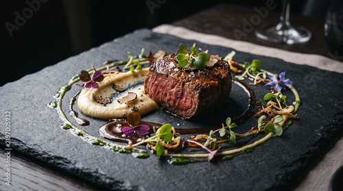 Gourmet beef steak served with truffle purée and fresh herb garnish on elegant black stone dinner plate.