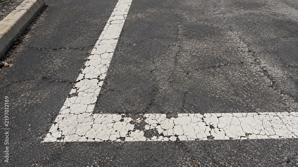 Obraz premium Damaged and Faded Parking Space Lines on Asphalt