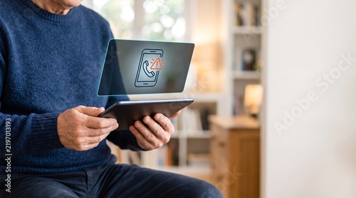 Senior man holding a tablet computer indoors.