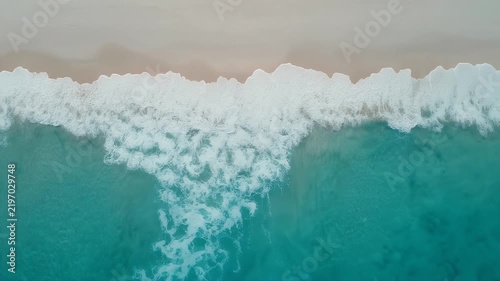 Aerial view of turquoise ocean waves crashing on a sandy beach.