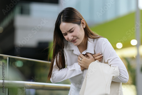 фотографія asian woman holding chest experiencing sudden severe pain heart attack showing d