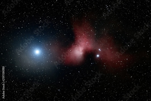 Bright blue star illuminates red cosmic dust clouds with distant stellar clusters