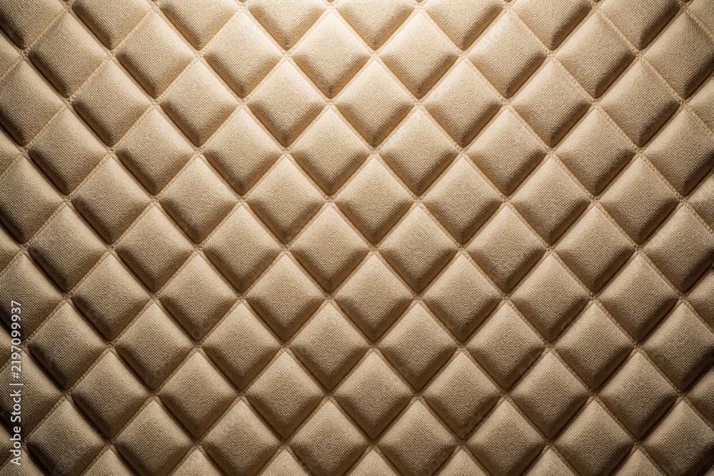Obraz premium Textured beige diamond pattern with fabric weave detail and soft light. This quilted surface offers a neutral, elegant background for design projects.