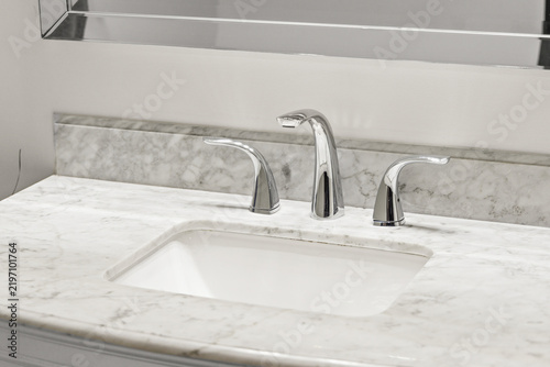 Принти на полотні Chrome bathroom faucet on white marble undermount sink