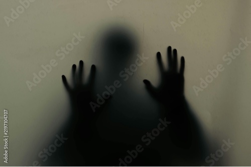 Fotografie Human silhouette behind frosted glass with hands pressed against surface