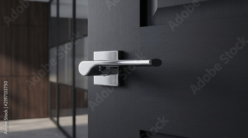 Modern chrome door handle on black interior door in luxury office interior design.