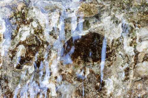 Water flowing over mossy wet rock surface