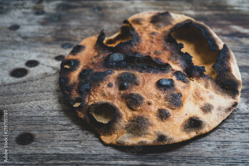 Burnt flatbread on rustic wooden table