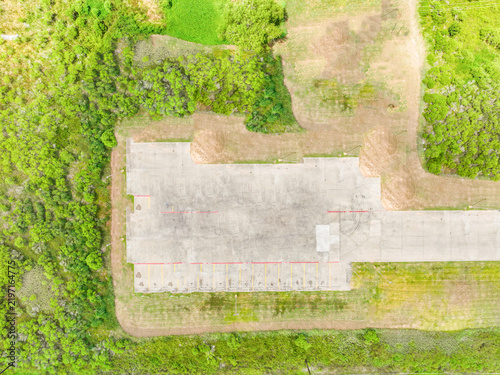Aerial top down view of a concrete platform surrounded by green grass with paved surface industrial site concrete slab landscape outdoors construction foundation environment daylight