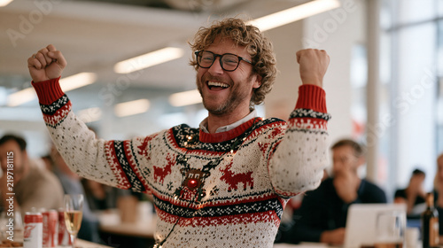 A disheveled man in a garish reindeer sweater with flashing lights pumping his fist at an office ugly sweater contest judging table on national ugly sweater day, workplace holiday